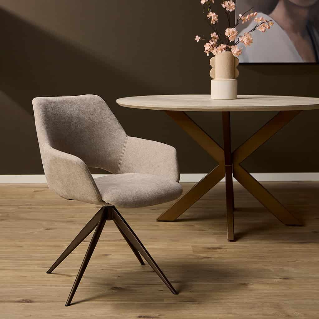 Eetkamerstoel van zacht beige stoffering met elegante draaivoet, gecombineerd met een modern eettafel met een houten blad en metalen pootconstructie, in een stijlvol wooninterieur.