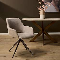 Eetkamerstoel van zacht beige stoffering met elegante draaivoet, gecombineerd met een modern eettafel met een houten blad en metalen pootconstructie, in een stijlvol wooninterieur.