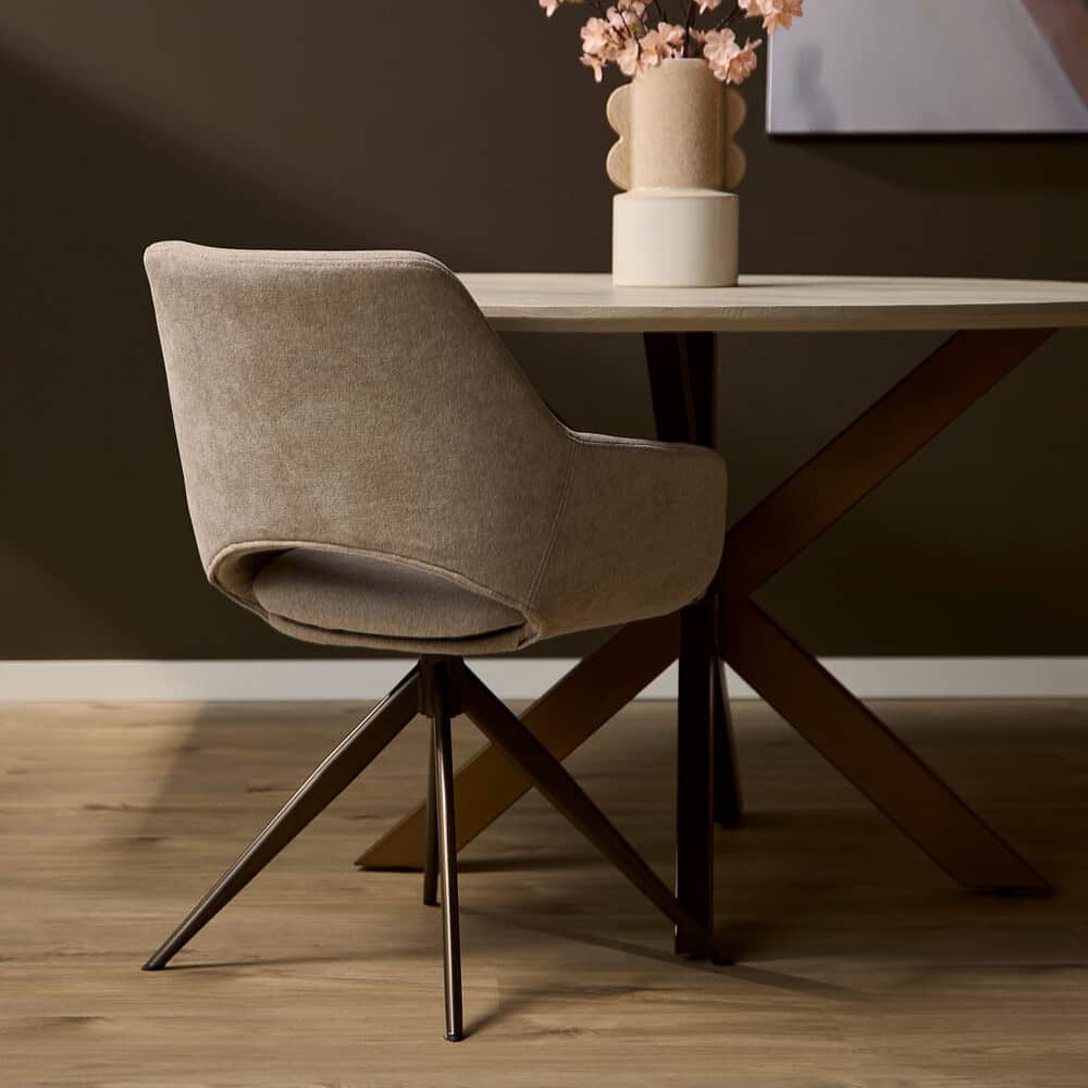 - Moderne eetkamerstoel met zachte, beige bekleding en zwarte metalen poten op een houten vloer en een stijlvolle eettafel met decoratieve vaas met bloemen.