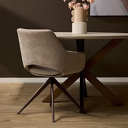 - Moderne eetkamerstoel met zachte, beige bekleding en zwarte metalen poten op een houten vloer en een stijlvolle eettafel met decoratieve vaas met bloemen.