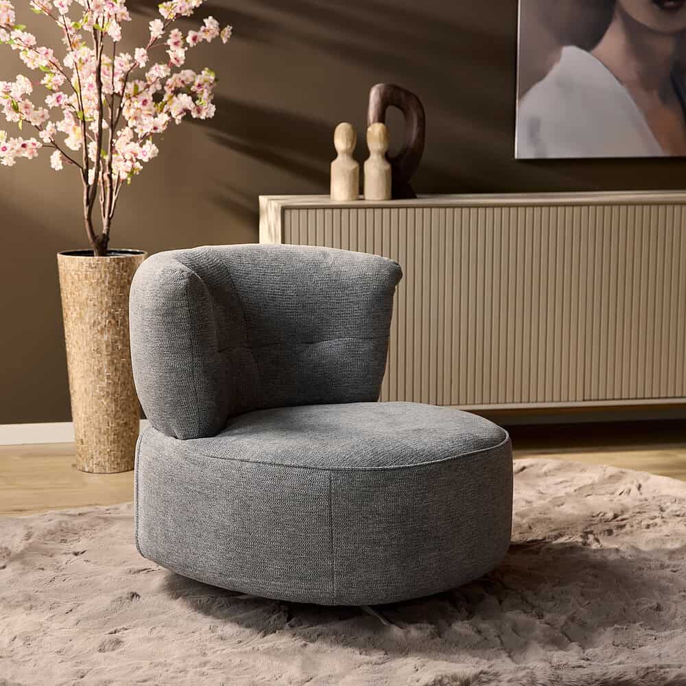 Relaxfauteuil in moderne woonkamer met houten vloer en beige wand, gecombineerd met vintage accessoires en een bloeiende kersenboom, perfect voor stijlvolle en comfortabele meubelbeleving.