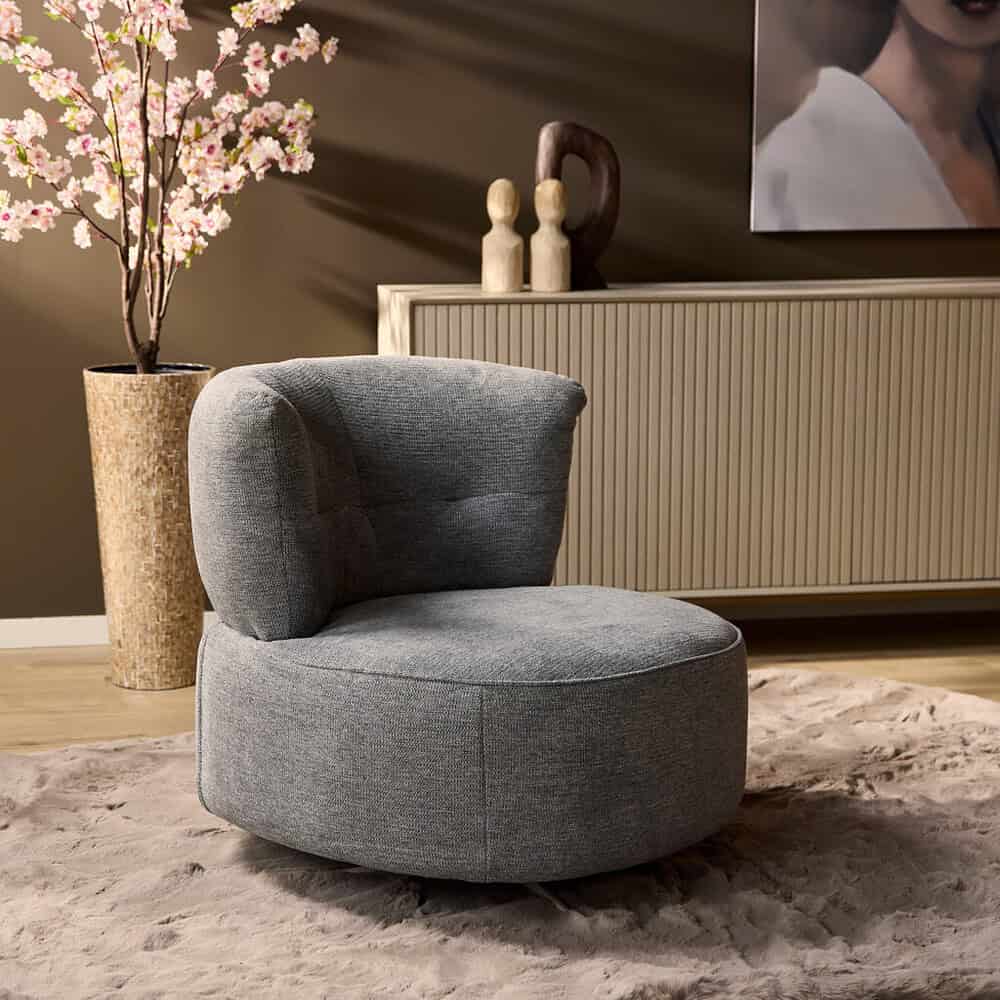 Zitstoel van zachte grijze stof in modern interieur, perfect voor woonkamer of lounge. Elegant design met comfortabele bekleding en houten details voor een warme sfeer.
