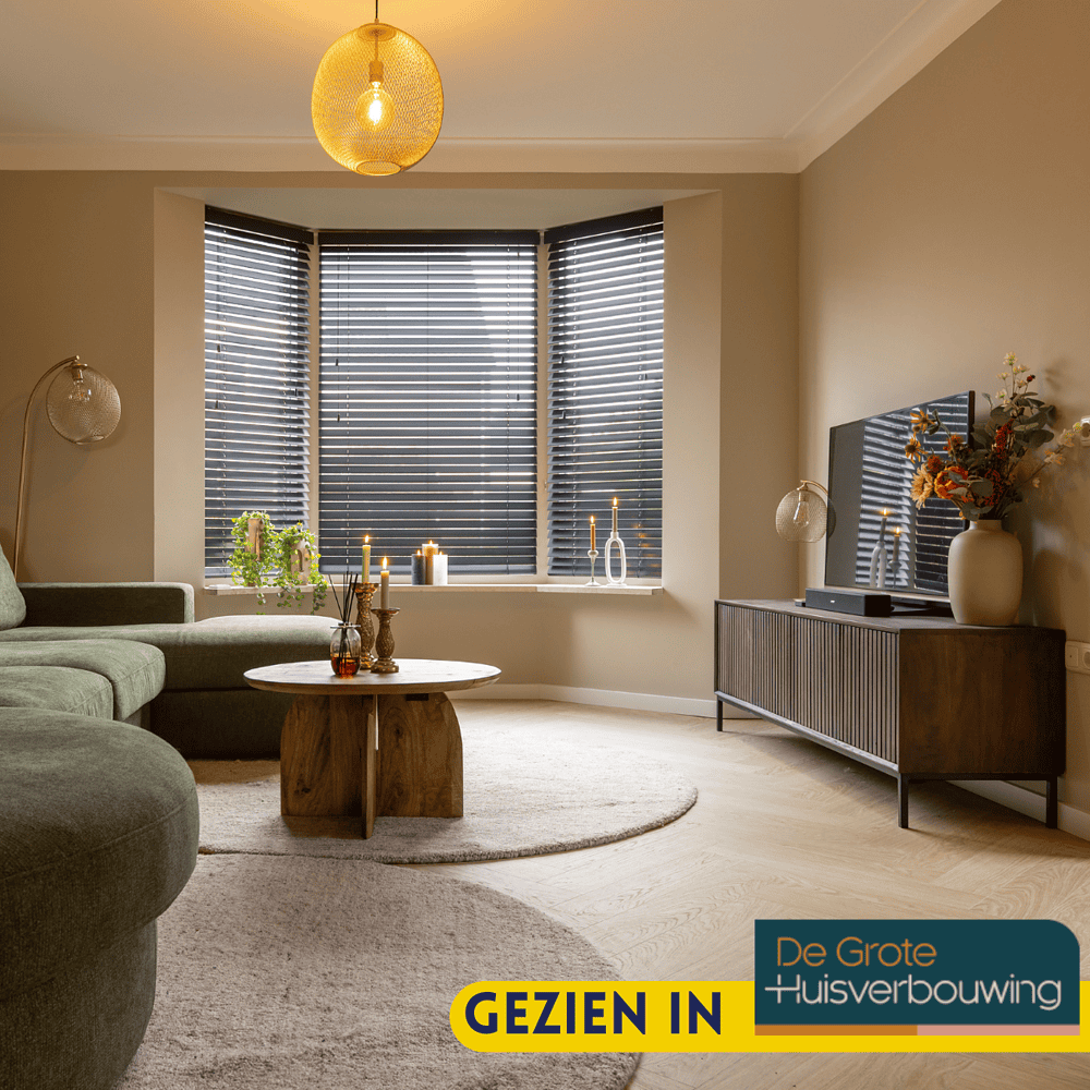 Stijlvolle woonkamer met moderne meubels, grote raampartijen met zwarte jaloezieën, gezellige verlichting en decoratieve accessoires voor een warm woninginterieur.