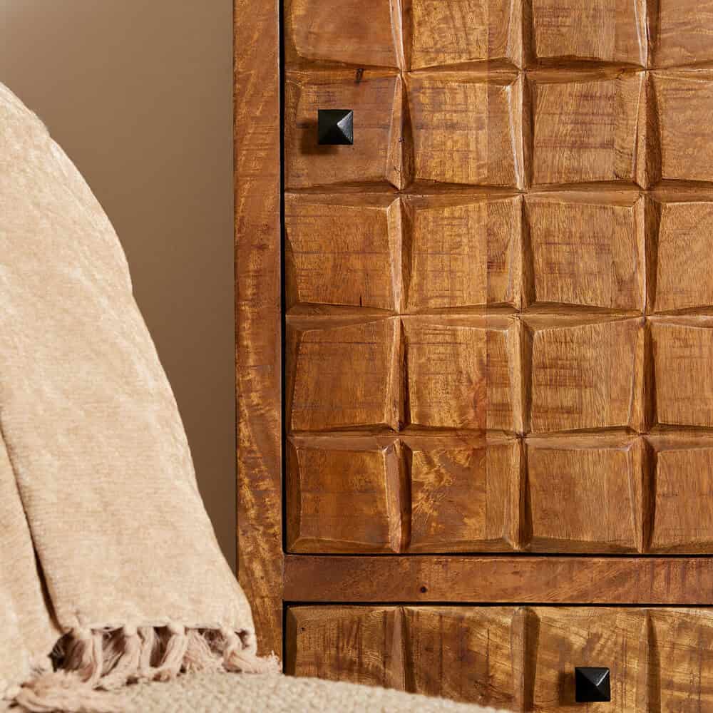 Authentieke houten meubel met gewaagde geometrische carving details en zwarte metalen knoppen, perfect voor een warme en stijlvolle interieurafwerking.
