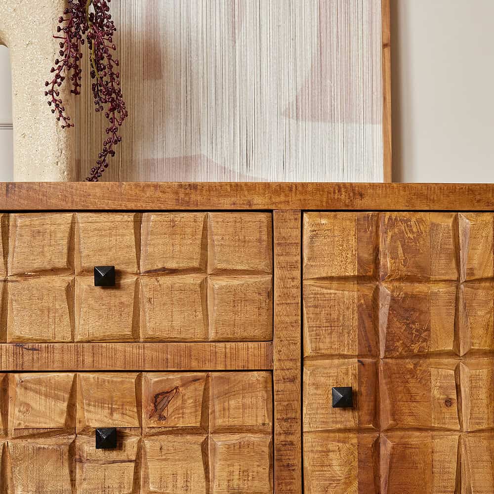 Elegante houten dressoir met gedreven details en zwarte knopknoppen, perfect voor het toevoegen van warmte en karakter aan ieder interieur.