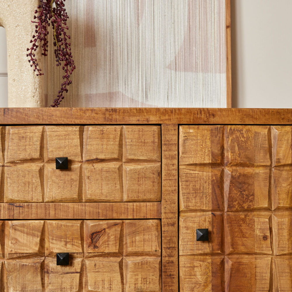 Robuuste houten ladekast met gedefinieerde patronen en zwart metalen knopdetails, perfect voor een gezellige en stijlvolle woonruimte.