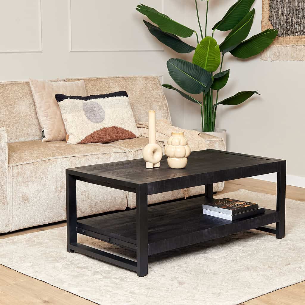 Tijdloze zwarte salontafel van massief hout in wooninterieur met beige bank en groene planten, modern industrieel design.