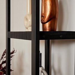 Modern interieur met zwarte stalen boekenplank en decoratieve vazen in keramiek en metaal.