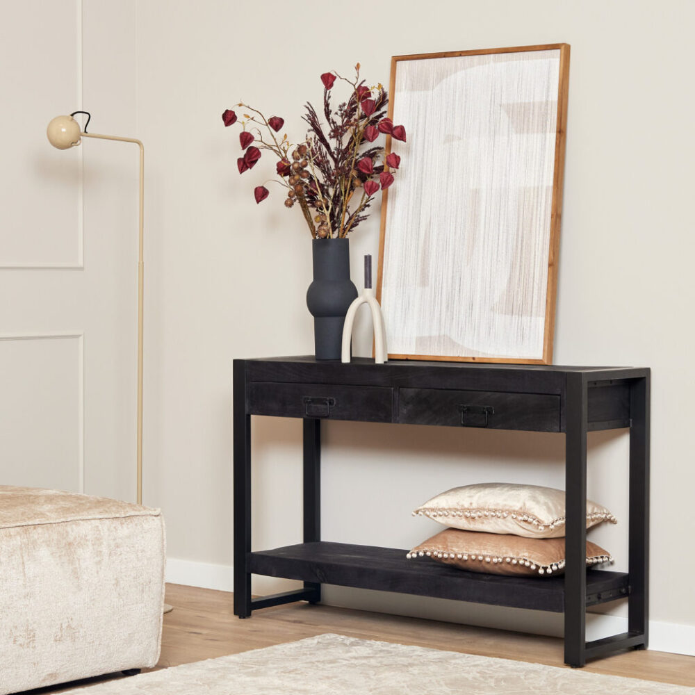 Bewerkt zwart houten console tafel met lades en onderste plank, decoratief met vazen en kussens, geschikt voor woon- of entree decoratie.