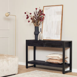 Bewerkt zwart houten console tafel met lades en onderste plank, decoratief met vazen en kussens, geschikt voor woon- of entree decoratie.