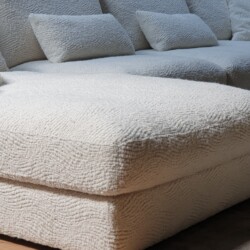 Knuffelige stoffen bank met zachte bekleding en comfortabele kussens, perfect voor ontspanning en loungen.