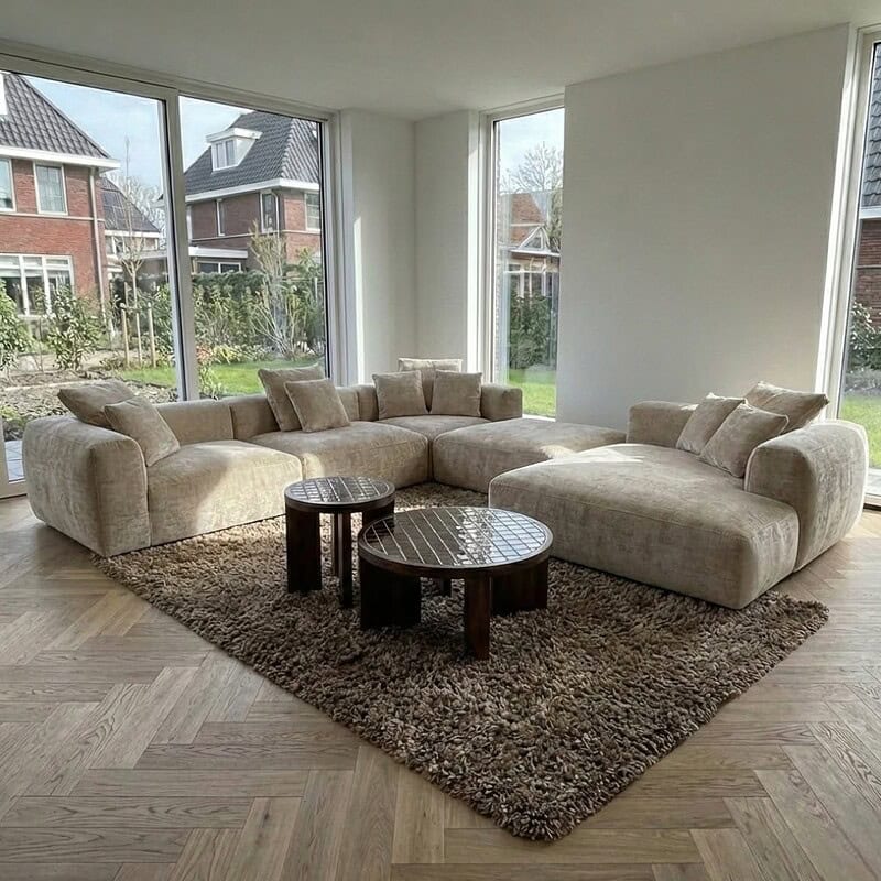1. Luxe stoffen hoekbank in een modern interieur met grote raampartijen en uitzicht op een groene tuin, perfect voor elegant wonen en comfort.