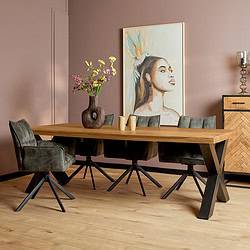 Robuuste houten eettafel met zwarte metalen onderstellen, omgeven door donkere velours stoelen en een kunstwerk aan de muur, perfect voor modern en gezellig dineren.
