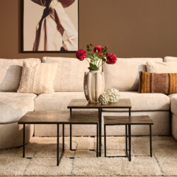 1. Elegante woonkamer met beige stoffen bank en bijzettafels, decoratief vazen met roze bloemen en kunst aan de muur voor een warm interieur.