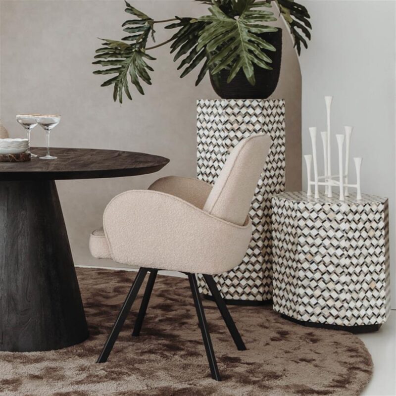 Zeer elegante en moderne eetkamerstoel met beige bekleding en zwarte houten poten, geplaatst in een stijlvolle interieursetting met decoratieve elementen en planten.