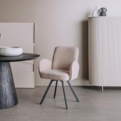 Zachte beige fauteuil met moderne zwarte poten in een minimalistisch interieur met witte kast en decoratieve vazen, perfect voor stijlvolle en comfortabele woonruimtes.