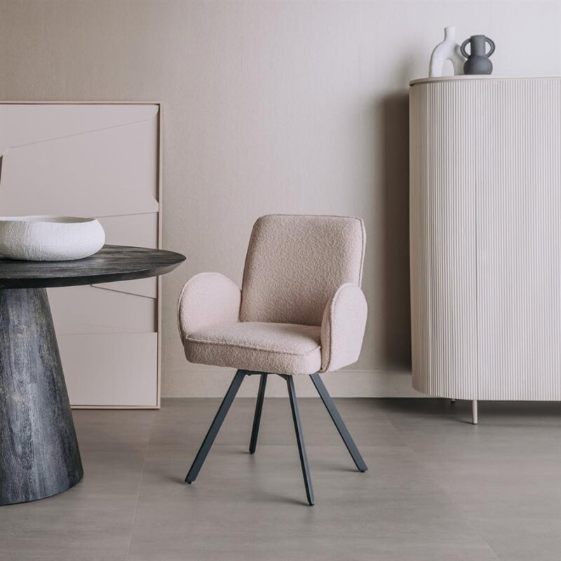 Zachte beige fauteuil met moderne zwarte poten in een minimalistisch interieur met witte kast en decoratieve vazen, perfect voor stijlvolle en comfortabele woonruimtes.
