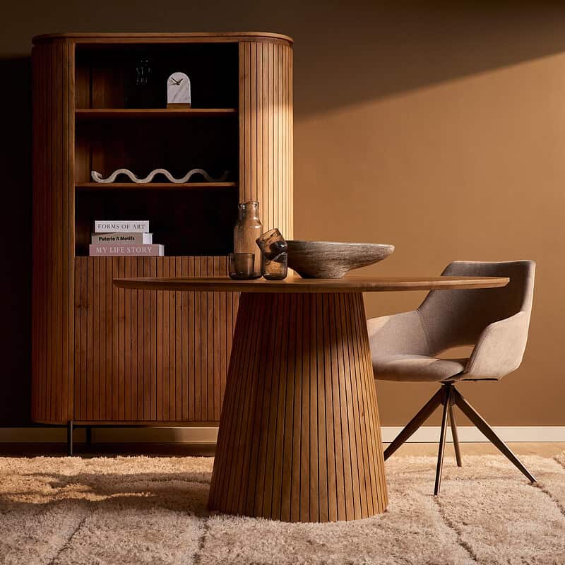 Eettafel Solana in naturel hout met ronde basis, gecombineerd met een moderne beige stoel, perfect voor een stijlvolle eetkamer.