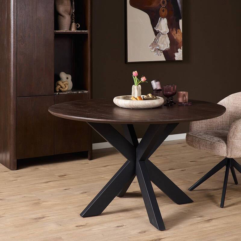 Eettafel Madison Brown met zwarte poot, 130 cm, in een modern interieur met houten vloer en decoratieve accessoires.