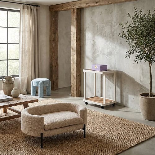 hondenbed-dolly-sheep-natural Moderne woonkamer met natuurlijke houten accenten, comfortabele beige fauteuil en grote planten voor een gezellige sfeer.