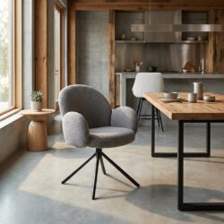Zeer comfortabele, moderne grijze lounge stoel met draaibaar onderstel, geplaatst in een lichte, natuurlijke keuken- en eetkameromgeving met grote ramen en houten accenten.