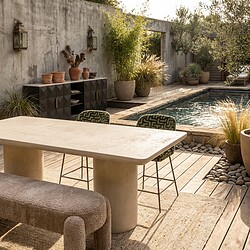 Een stijlvolle buitenruimte met een modern tafel en comfortabele stoelen, omringd door planten en een zwembad, perfect voor ontspanning en buiten dineren.