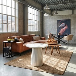 Moderne woonkamer met bank, ronde tafel en decoratieve accessoires in een industrieel interieur.