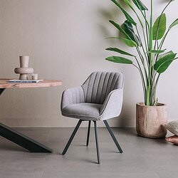 Moderne Bruno armstoel met draaibare functie, bekleed met Nature stof 452 in blauwgrijs, geplaatst in een minimalistische interieursetting met een grote groene plant.