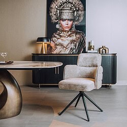 Moderne fauteuil met zachte bekleding en zwarte metalen poten, geplaatst in een stijlvolle woonkamer met kunstwerk en decoratieve accessoires.