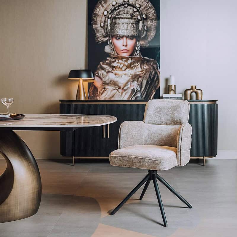 Moderne fauteuil met zachte bekleding en zwarte metalen poten, geplaatst in een stijlvolle woonkamer met kunstwerk en decoratieve accessoires.