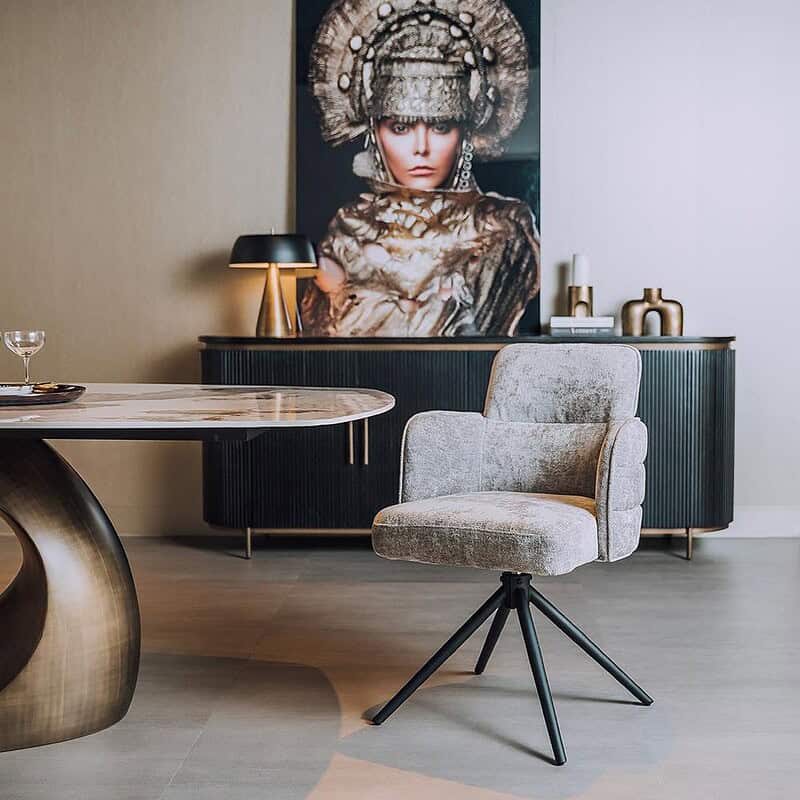 Moderne woonkamerinrichting met een comfortabele, lichtgrijze fauteuil en een elegante eettafel, aangevuld met decoratieve accessoires en kunstwerken voor een luxe uitstraling.