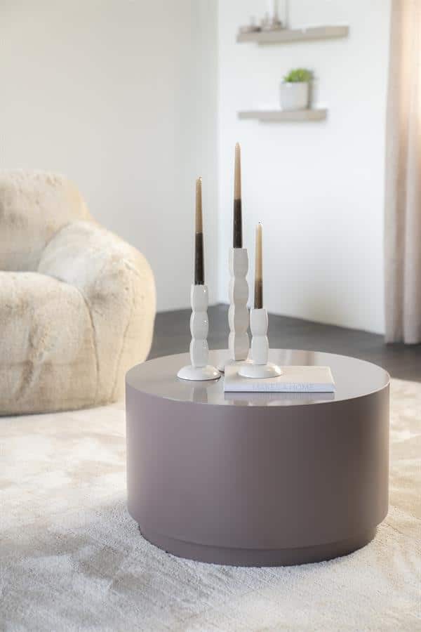 Ein gemütliches Interieur mit einem runden Couchtisch und Kerzenständern in einem hellen, minimalistischen Wohnzimmer.