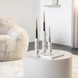 Moderner weißer runder Couchtisch in einem hellen Wohnzimmer, geschmückt mit drei Kerzen und einem Buch – perfekt für eine schlichte und stilvolle Einrichtung.