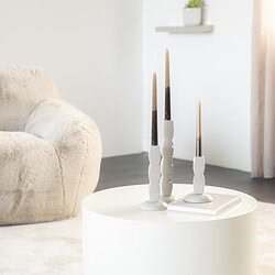 Ein eleganter weißer Kerzenständer mit drei Kerzen auf einem runden weißen Tisch in einem minimalistischen Interieur – perfekt für moderne Wohnkultur.