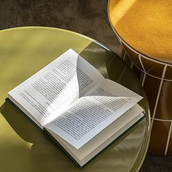 Moderner grüner Beistelltisch mit einem aufgeschlagenen Buch darauf, in einer stilvollen Einrichtung. Perfekt als Wohnaccessoire und für den praktischen Gebrauch.