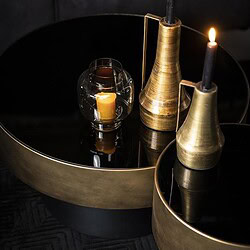 Goldene Kerzenständer mit brennenden Kerzen auf stilvollen Beistelltischen – perfekt für eine luxuriöse Einrichtung.