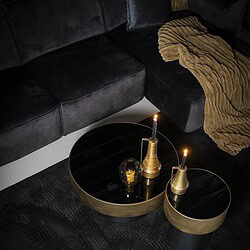 Moderne schwarze Couchtische mit goldenen Details und Kerzen auf einem schwarzen Teppich – perfekt für ein stilvolles Wohnzimmer.