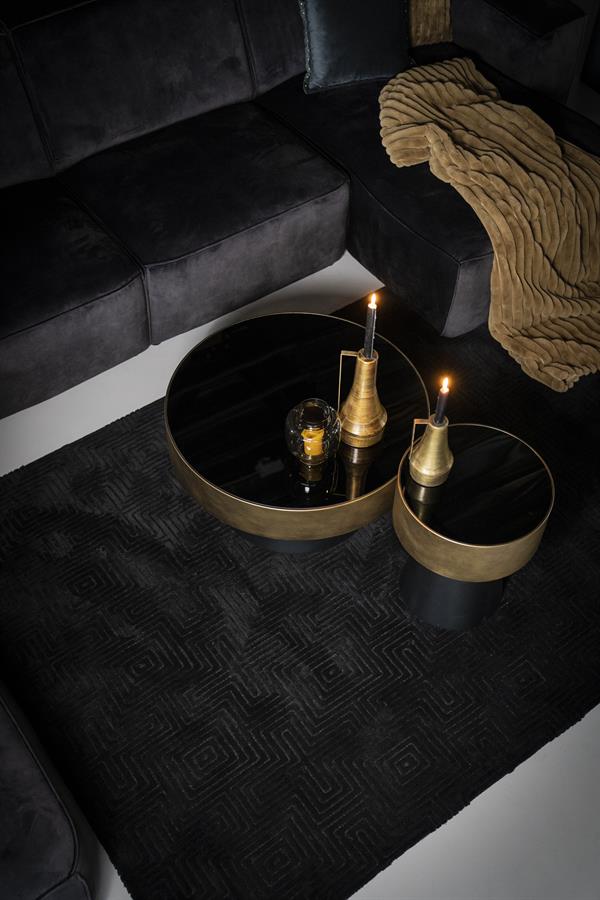 Moderne schwarze Couchtische mit goldenen Details und Kerzen auf einem schwarzen Teppich – perfekt für ein stilvolles Wohnzimmer.