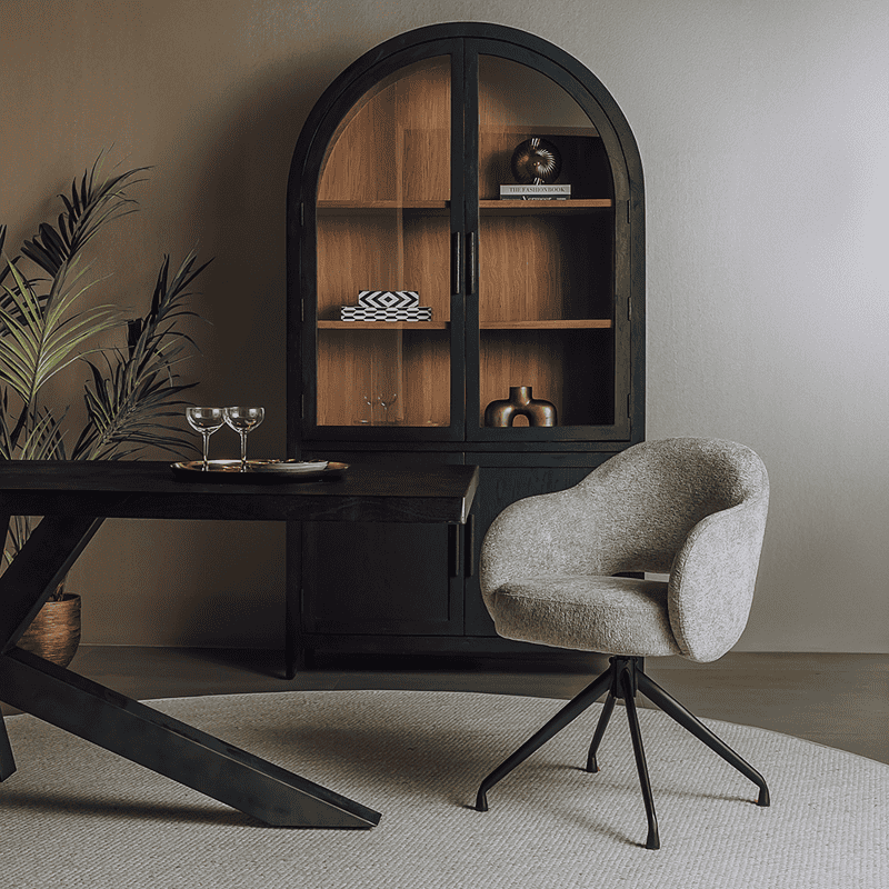 Een stijlvolle vintage houten kast met zwarte afwerking, geplaatst in een modern interieur met een comfortabele bureaustoel en decoratieve accessoires.