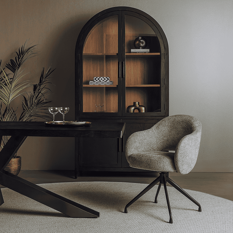 Vintage houten kast met glazen deuren, decoratieve accessoires en een moderne stoel in een stijlvolle woonkamer. Perfect voor het opbergen en tonen van decoratie.