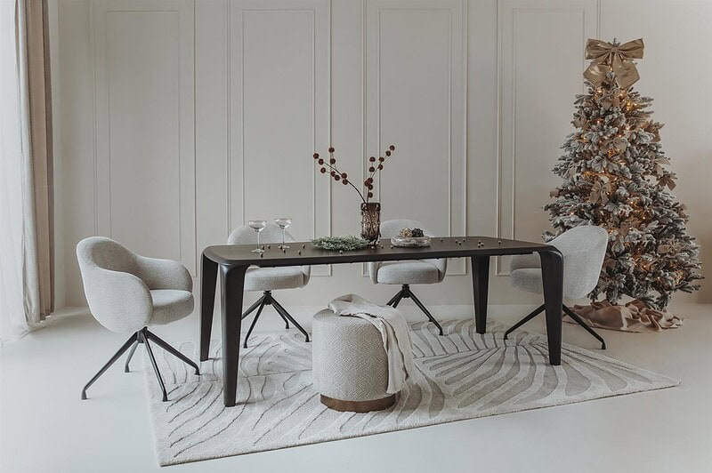 Een stijlvolle eettafel met comfortabele moderne stoelen in een lichte, minimalistische eetkamer, versierd met een kerstboom voor de feestdagen.