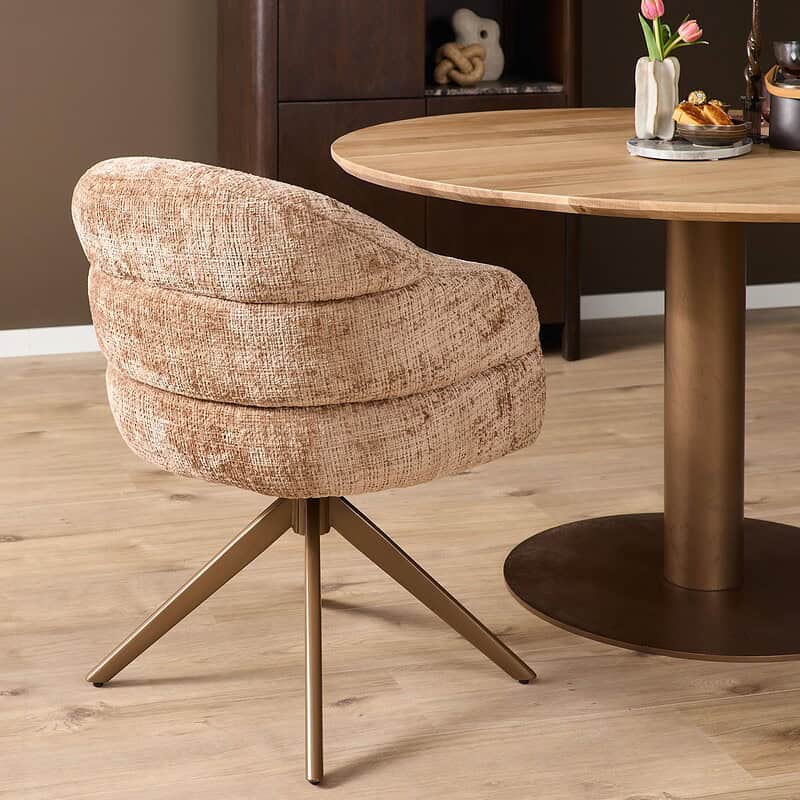 Ontdek de stijlvolle Mokana Bella eetkamerstoel met armleuning in een warme cinnamon kleur, voorzien van een elegante bronzen poot voor een moderne uitstraling.