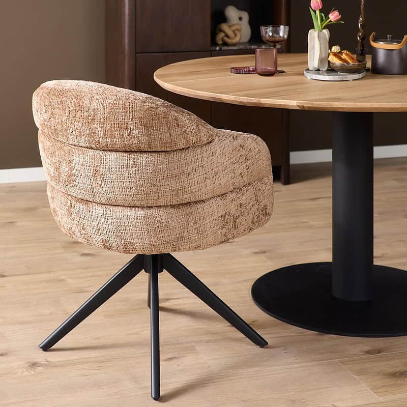 Comfortabele eetkamerstoel Bella in cinnamon stof met zwarte poot, armleuningen en draaibaar ontwerp, perfect voor een stijlvolle en gezellige eethoek.