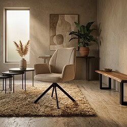 Comfortabele beige fauteuil met houten pootjes in een stijlvolle woonkamer, omringd door natuurlijke decoratie en minimalistisch meubilair.