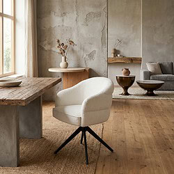 Moderne draaibare eetkamerstoel in off-white stof met zwarte poot, geplaatst in een minimalistisch interieur met natuurlijke materialen.