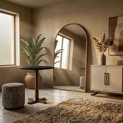 Modern interieur met spiegel, planten en houten meubel in een lichte kamer.