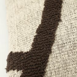 Close-up van een kussen met een gebreide rand en zachte textuur, perfect voor een gezellige woonkamer of slaapkamer.