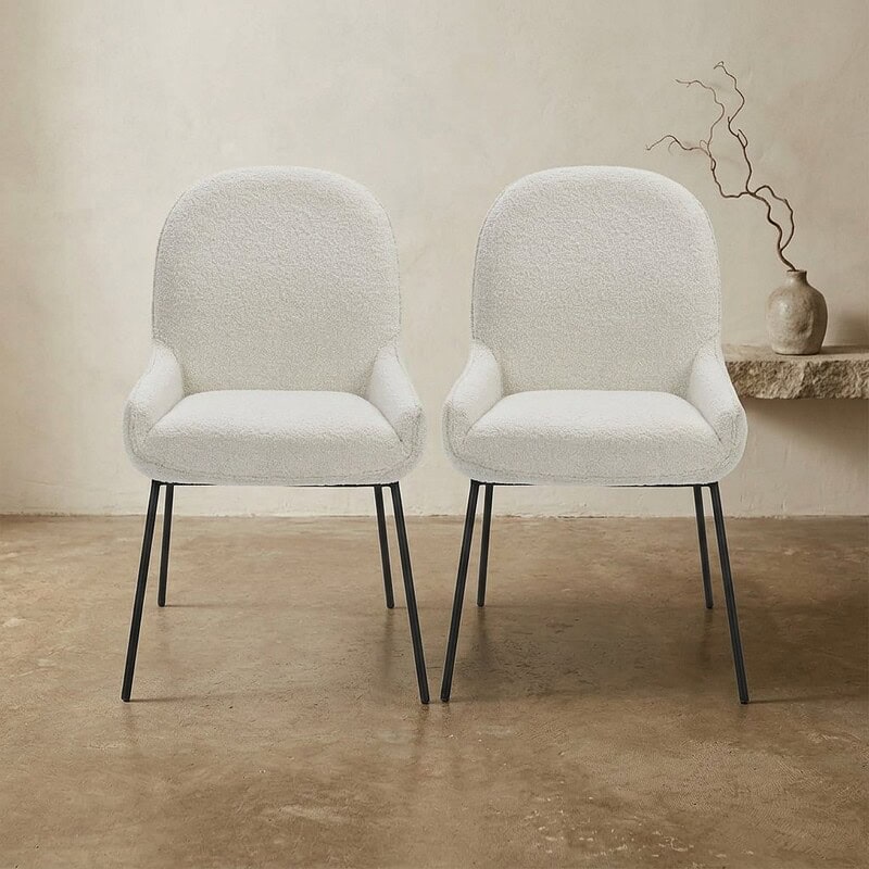 Twee witte Scandinavische fauteuils met houten poten in een minimalistische interieursetting, perfect voor modern en comfortabel wonen.
