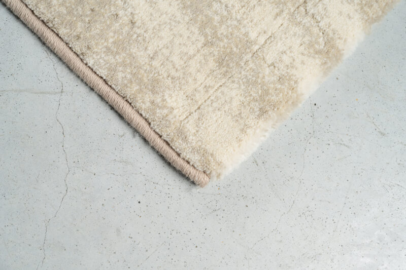 Beige vloerkleed van hoge kwaliteit op betonnen vloer, perfect voor een moderne woonkamer of slaapkamer, voegt warmte en stijl toe aan elk interieur.