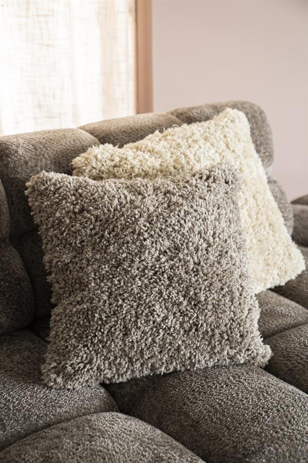 Drie fluffy sierkussens in neutrale tinten op een moderne bank, perfect voor comfort en stijl in je woonkamer.